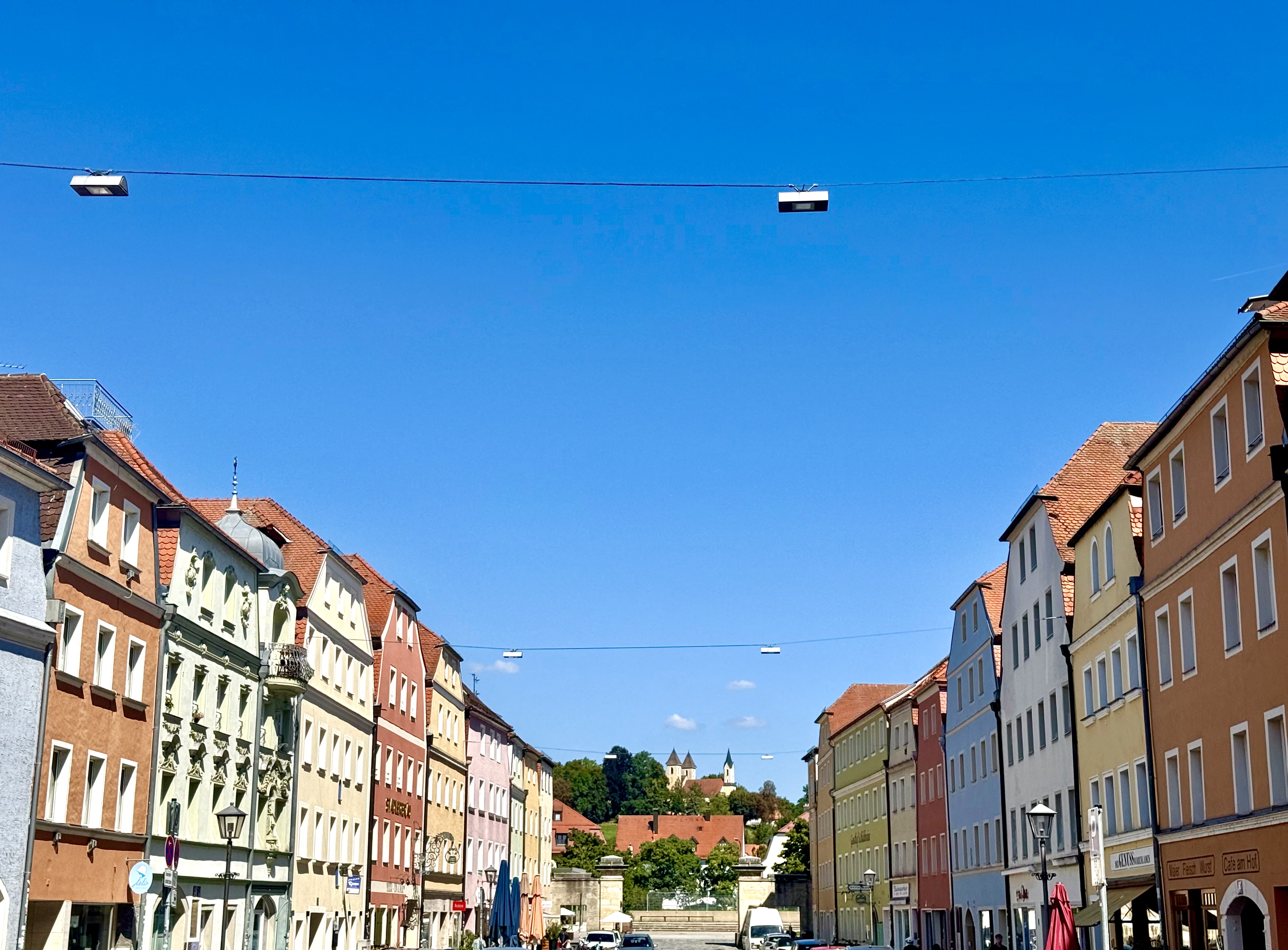 Historische Straße in Regensburg mit bunten Gebäuden und Blick auf die Kirche